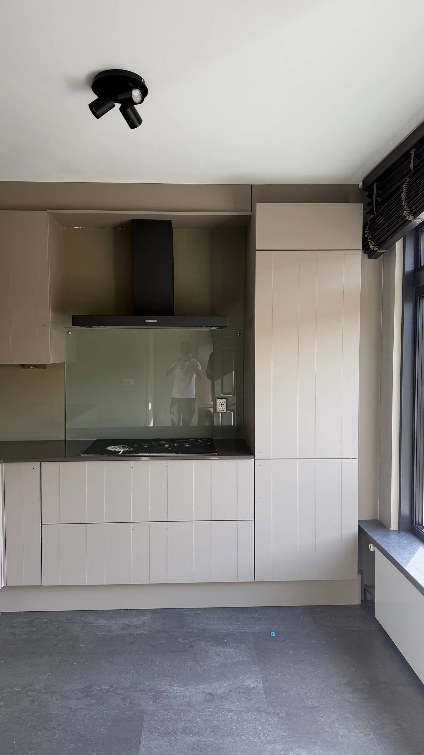 Gewrapte keuken in Heenvliet met taupe fronten, zwarte afzuigkap en groene glazen achterwand