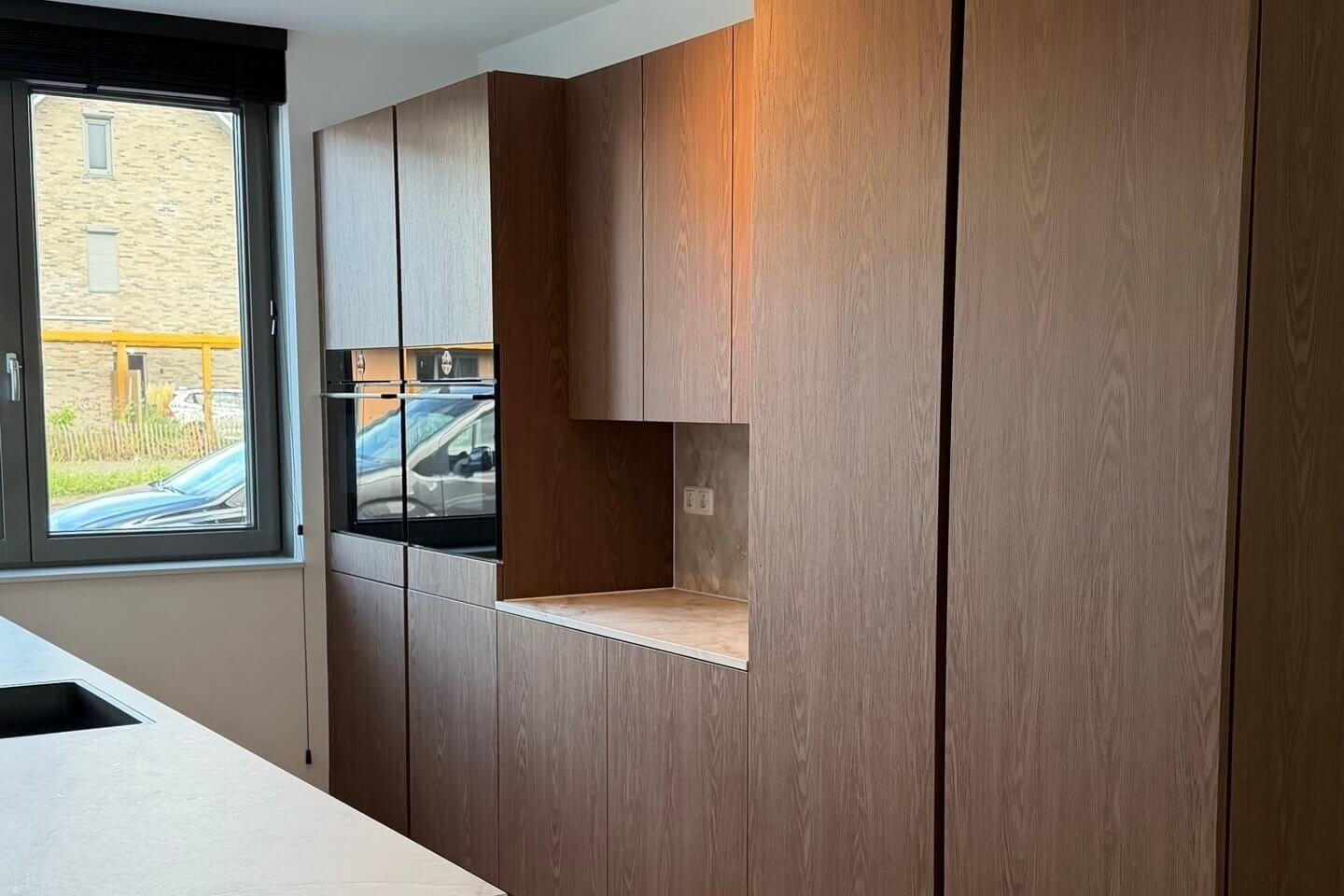 Gewrapte keuken in Japandi stijl met kastenwand in een warme donkere houtlook