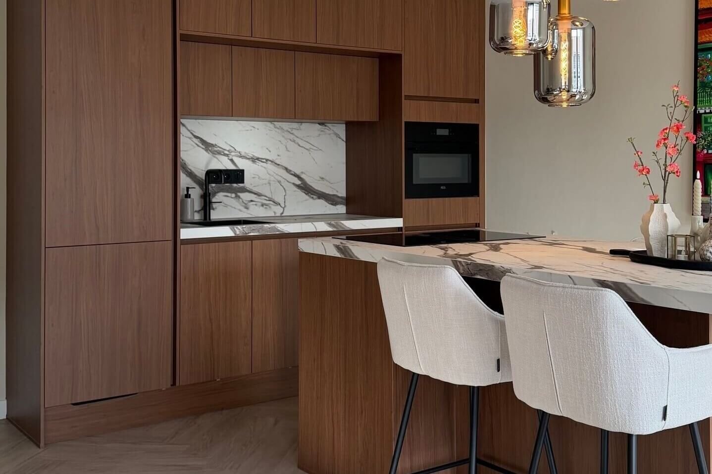 Keuken wrappen of een nieuwe keuken Gewrapte keuken in een warme houtlook met kookeiland en barkrukken