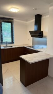 Gewrapte keuken in Rotterdam met kastjes in de houtlook Hazel 2.0 en een werkblad in Onyx gold marmerlook