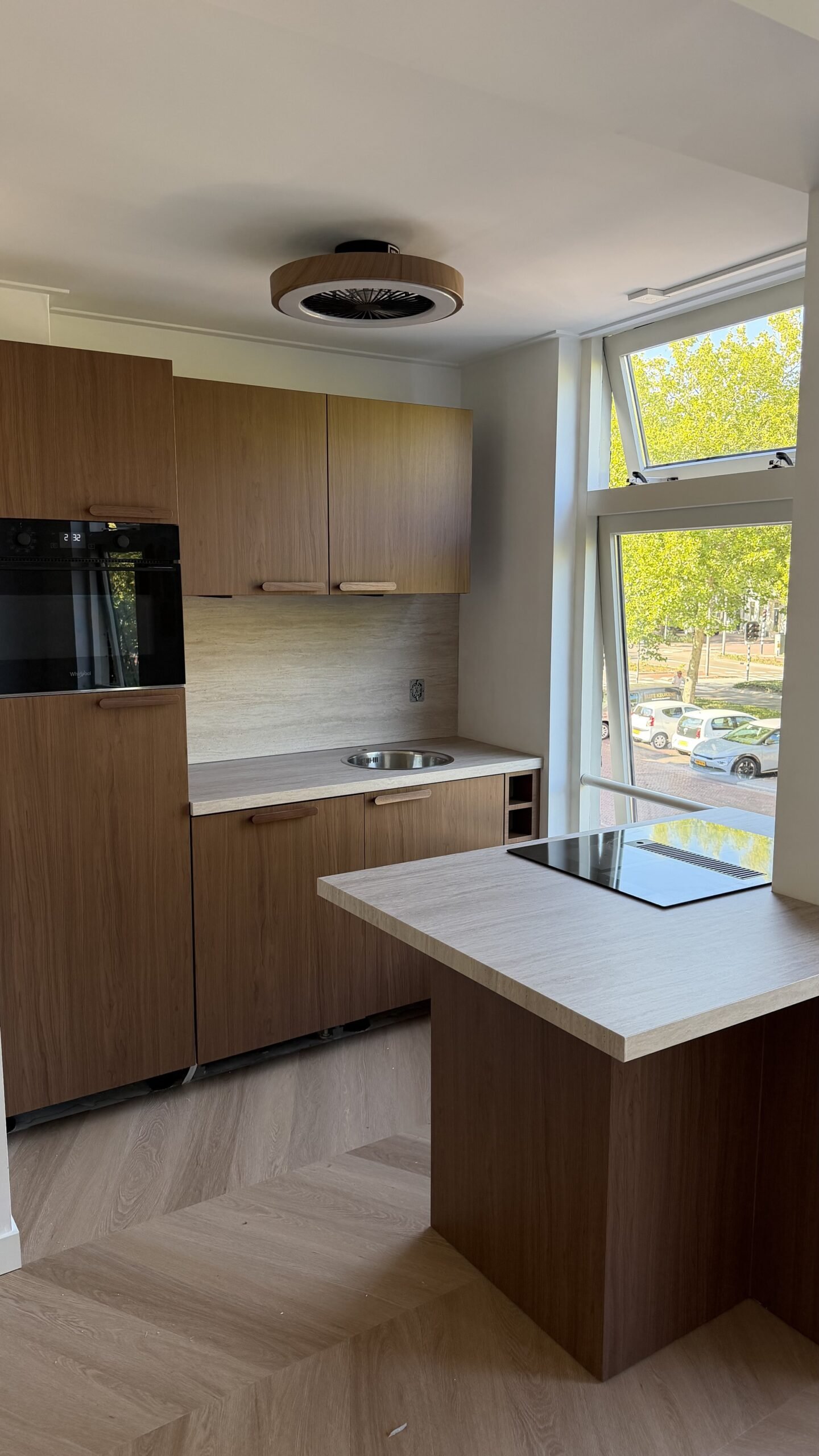 Gewrapte keuken in Purmerend met keukenkasten in een warme houtlook met een licht werkblad