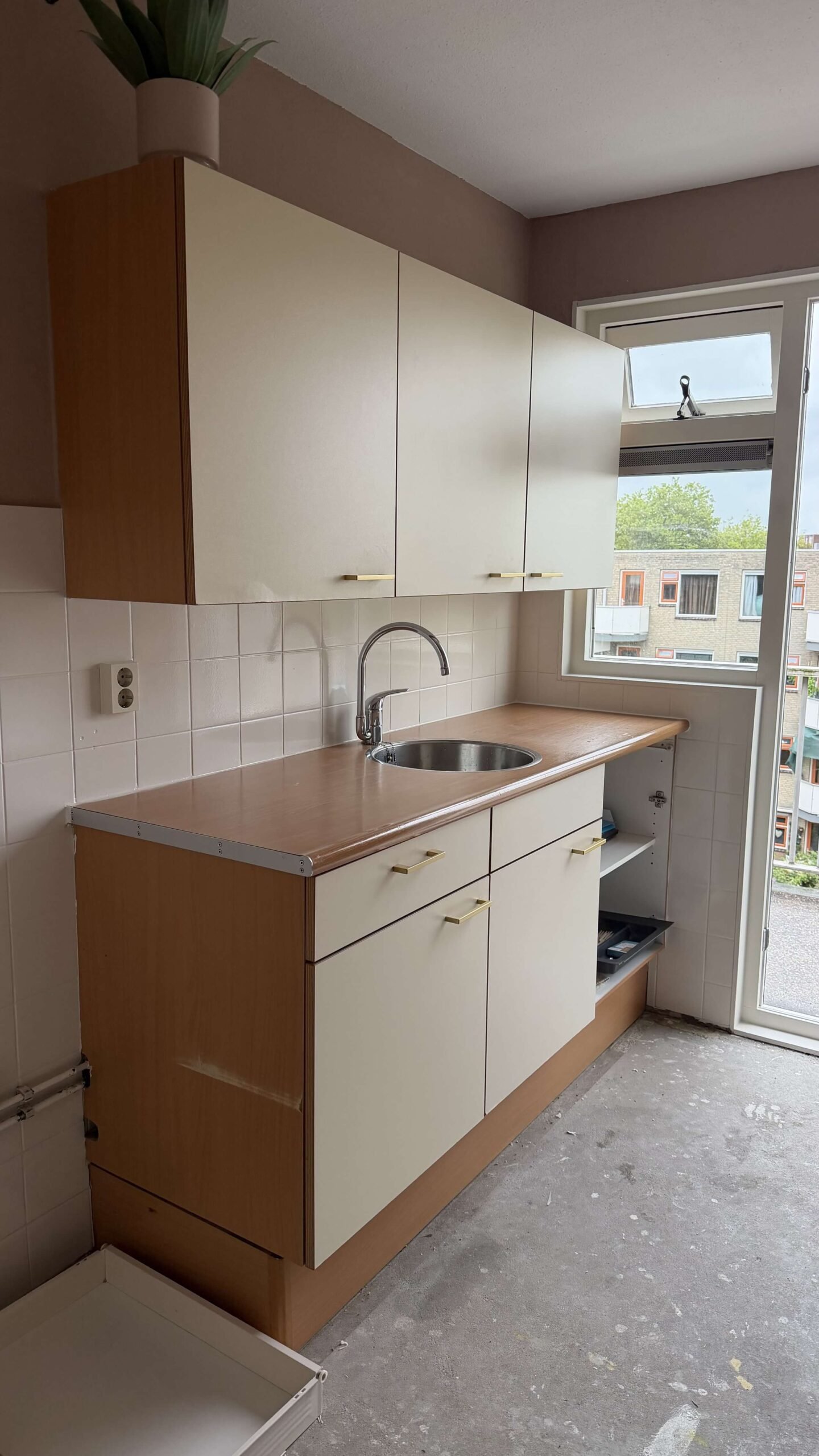Keuken in Maassluis voor het wrappen, met een crèmekleurige keuken met houten bovenkast