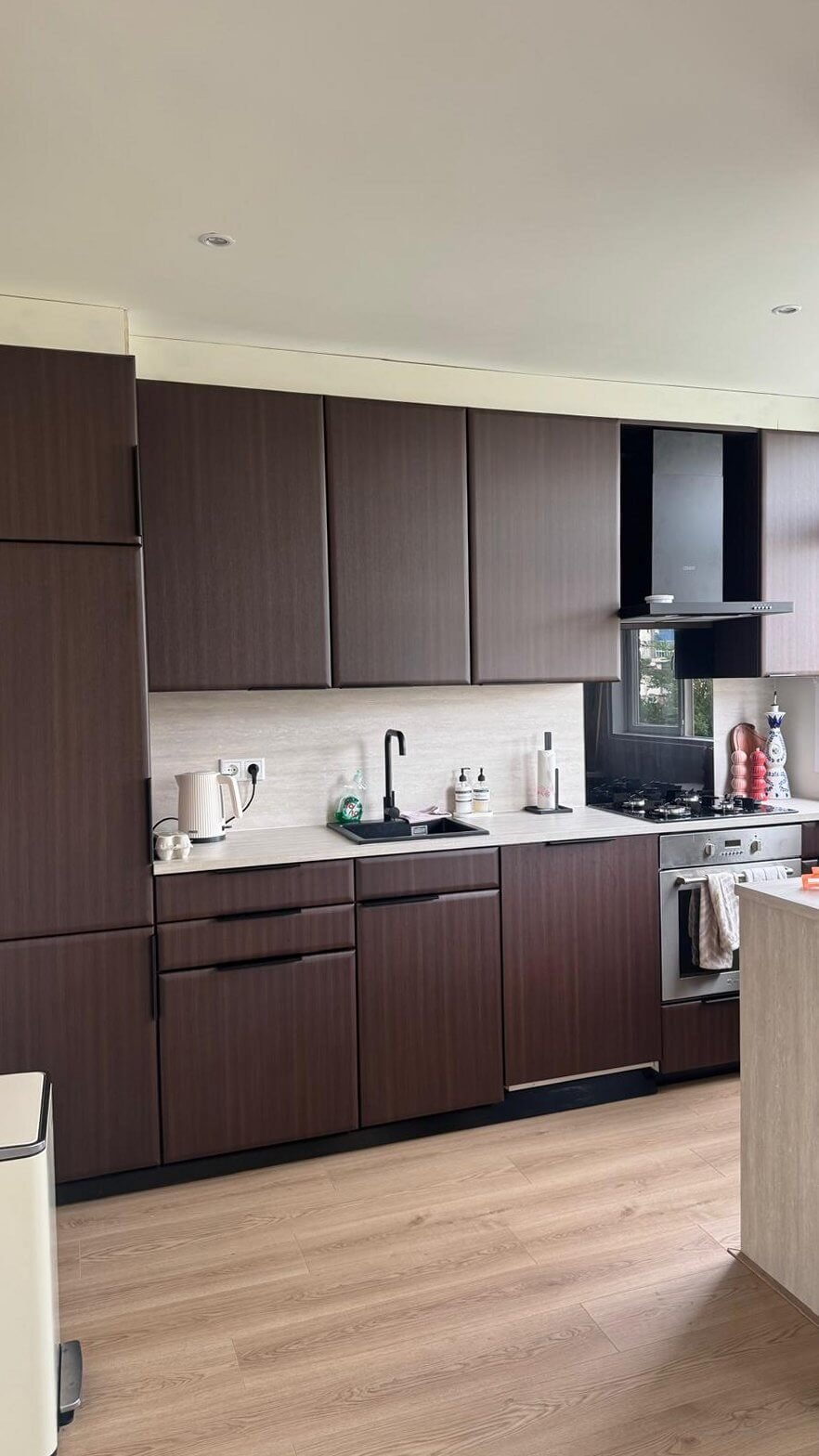Gewrapte keuken in Schiedam met kasten in de warme donkere houtlook Chestnut en een lichte achterwand, met de vaatwasser en de plinten erbij