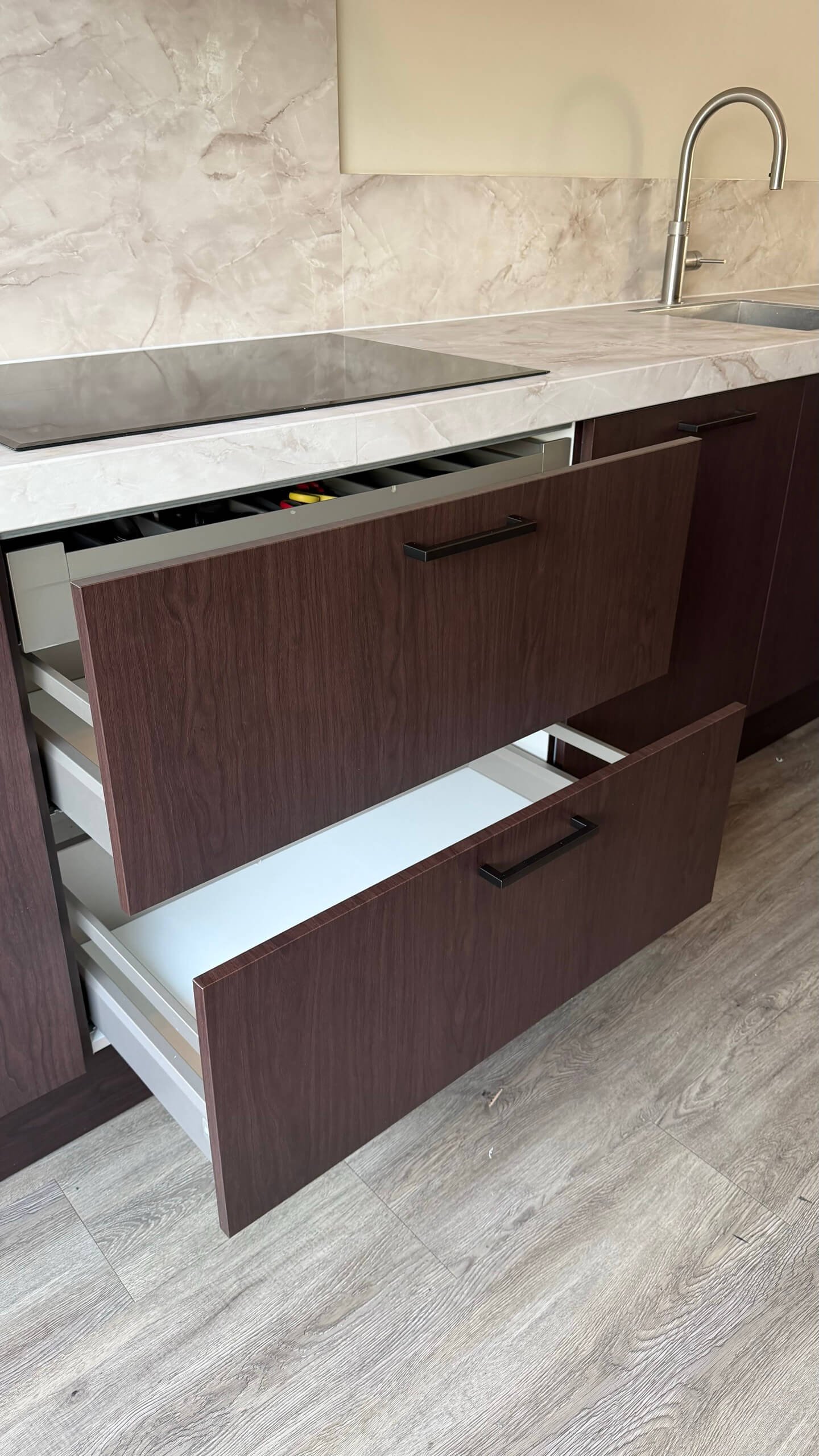 Open lades met fronten in de donkere houtlook Navis onder een werkblad in de marmerlook Onyx gold