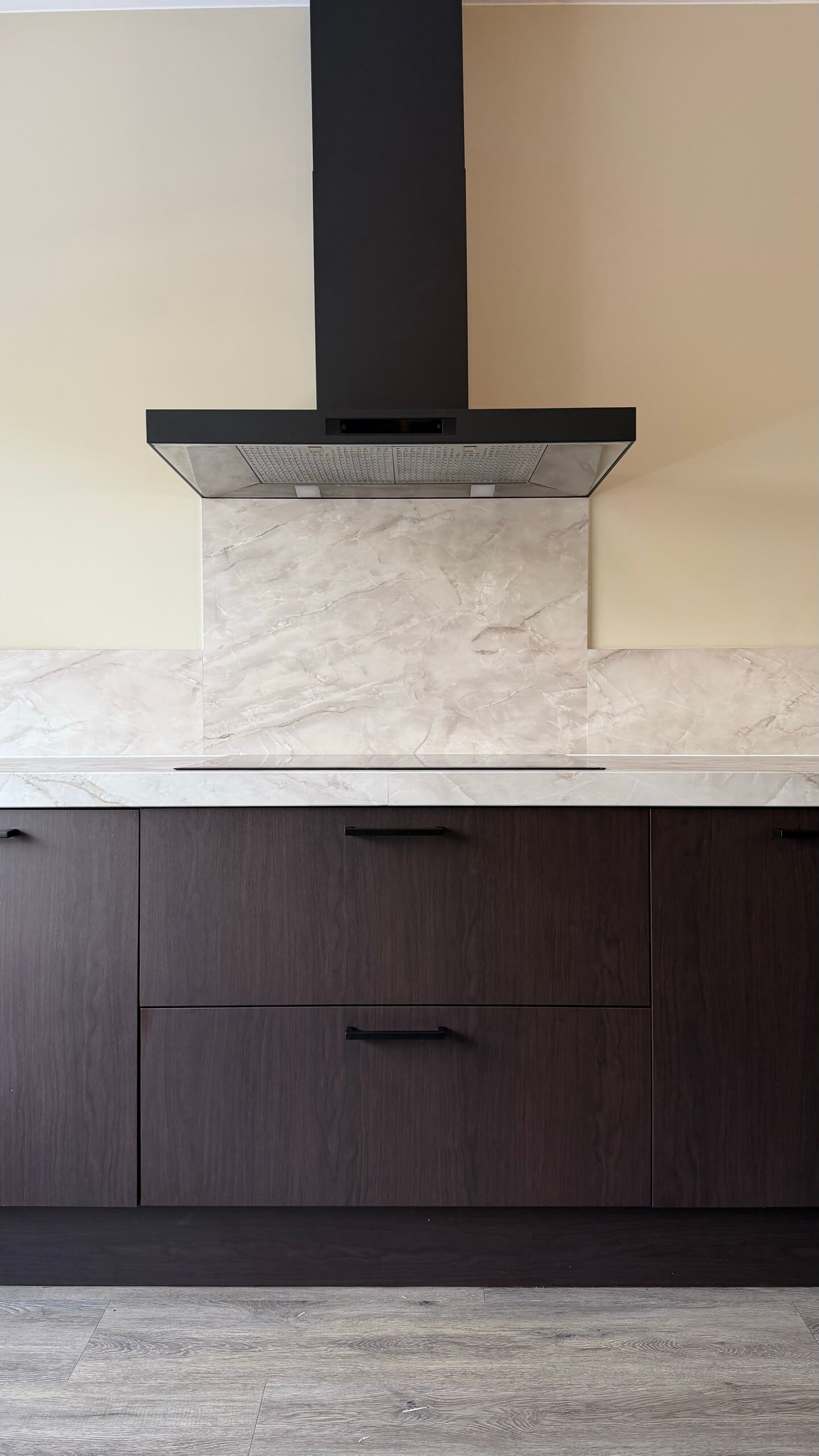 Afzuigkap gewrapt in Pantera boven een achterwand en werkblad in de marmerlook Onyx gold